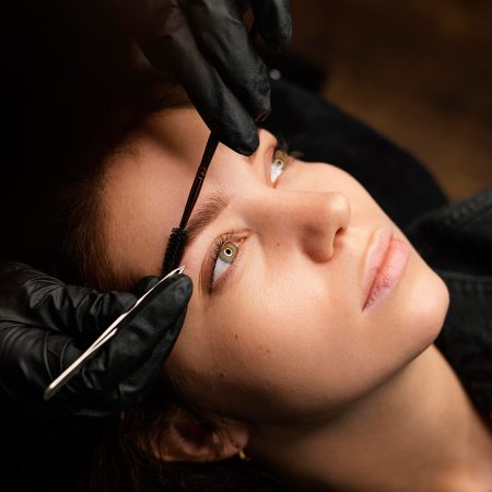 high-angle-female-clinician-doing-eyebrow-treatment-female-customer